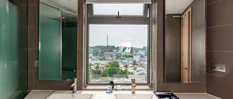 Een badkamer met twee wasbakken, een grote spiegel en een raam met uitzicht over de stad.