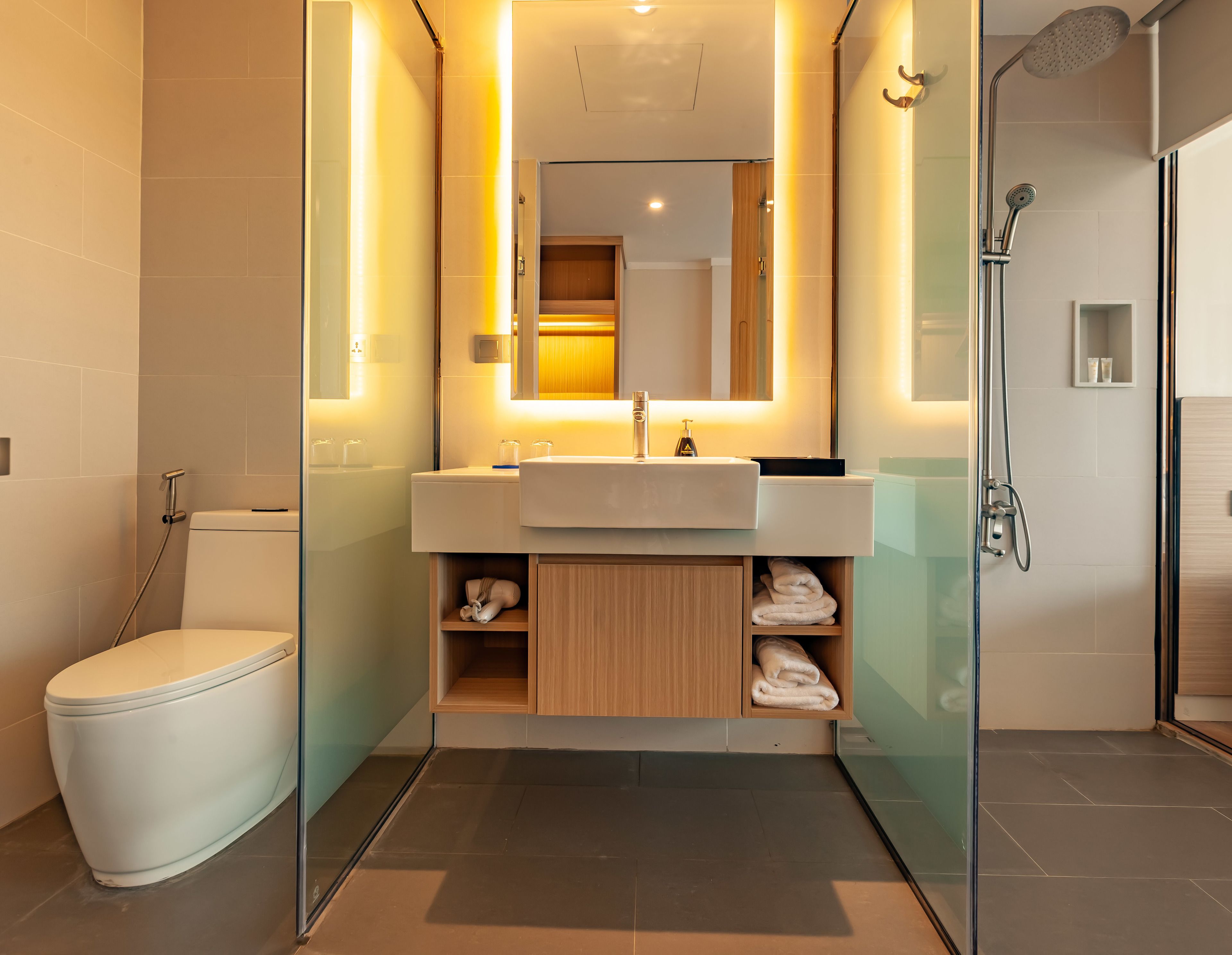 Een moderne badkamer met een douchecabine van glas, een wit toilet en een wastafelmeubel met een spiegel erboven.