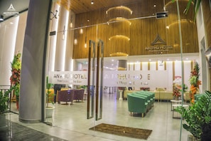Eine Hotelhalle mit Empfangstresen, Sitzgelegenheiten und Zierpflanzen.
