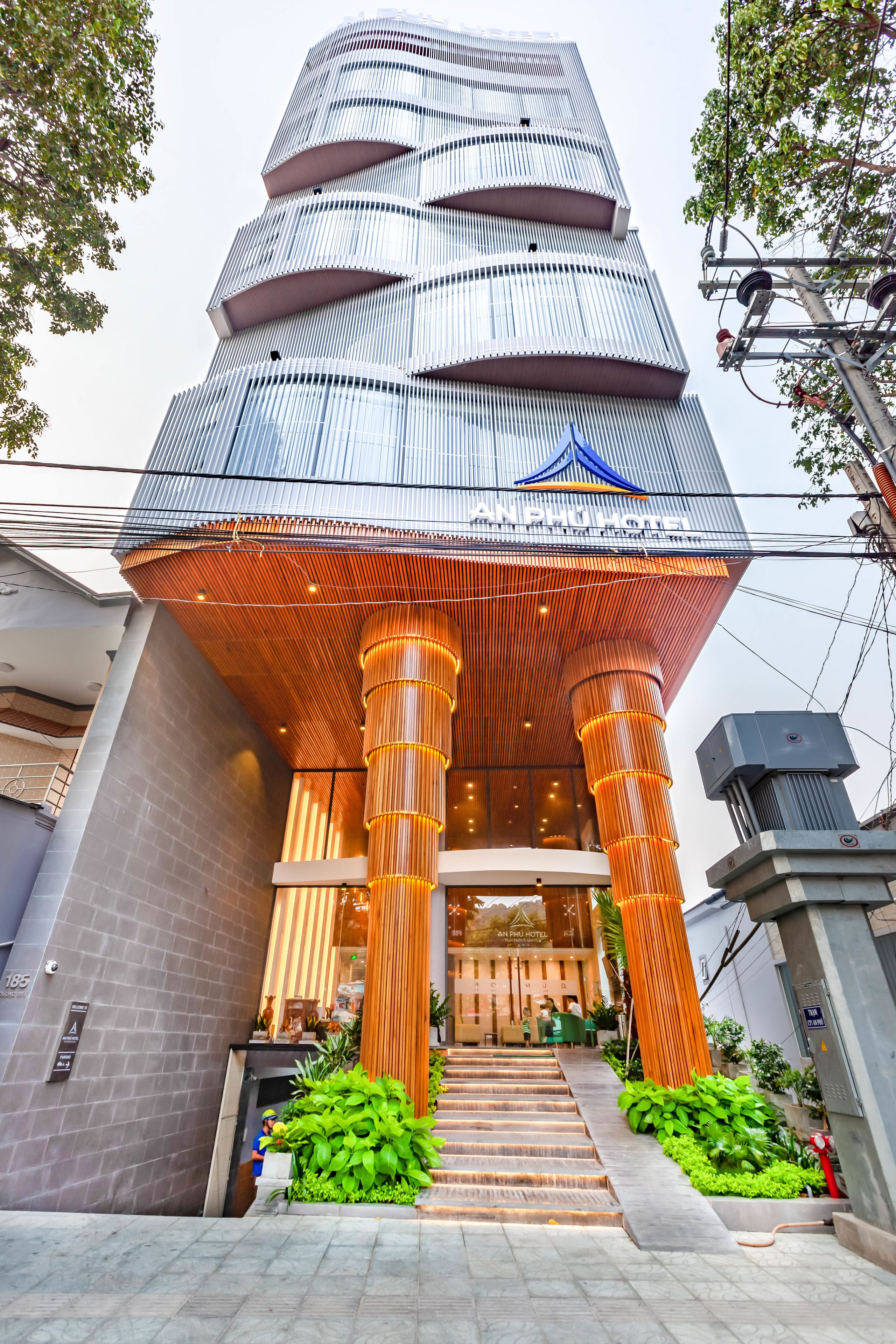 Um hotel moderno com um design cilíndrico único, apresentando uma entrada destacada com ripas verticais de madeira e fachada de vidro.