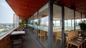 A modern hotel restaurant with glass walls, wooden ceiling, and outdoor seating. - An Phu Hotel (Phu Quoc)