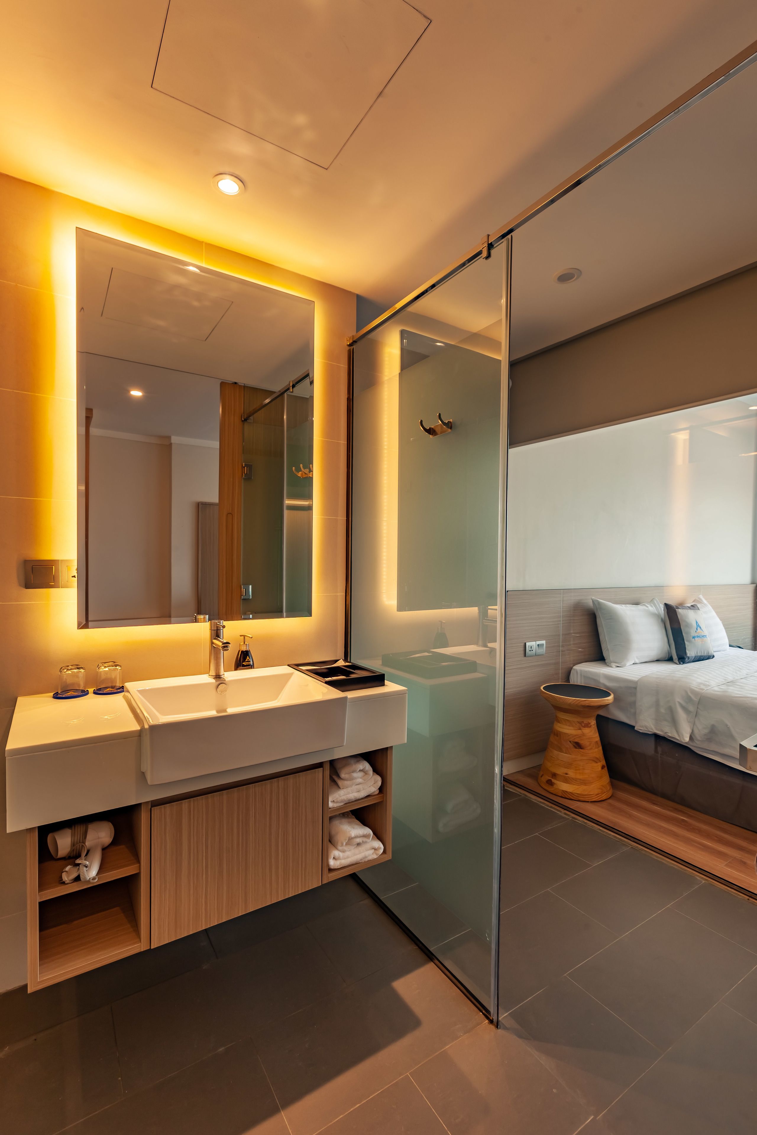 Une salle de bain moderne avec un grand miroir, un lavabo blanc et une douche à parois de verre.
