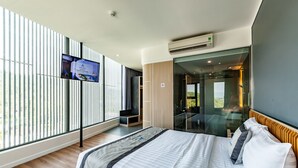 A modern hotel room with a large bed, a TV mounted on the wall, and a sliding glass door leading to a balcony. - An Phu Hotel (Phu Quoc)