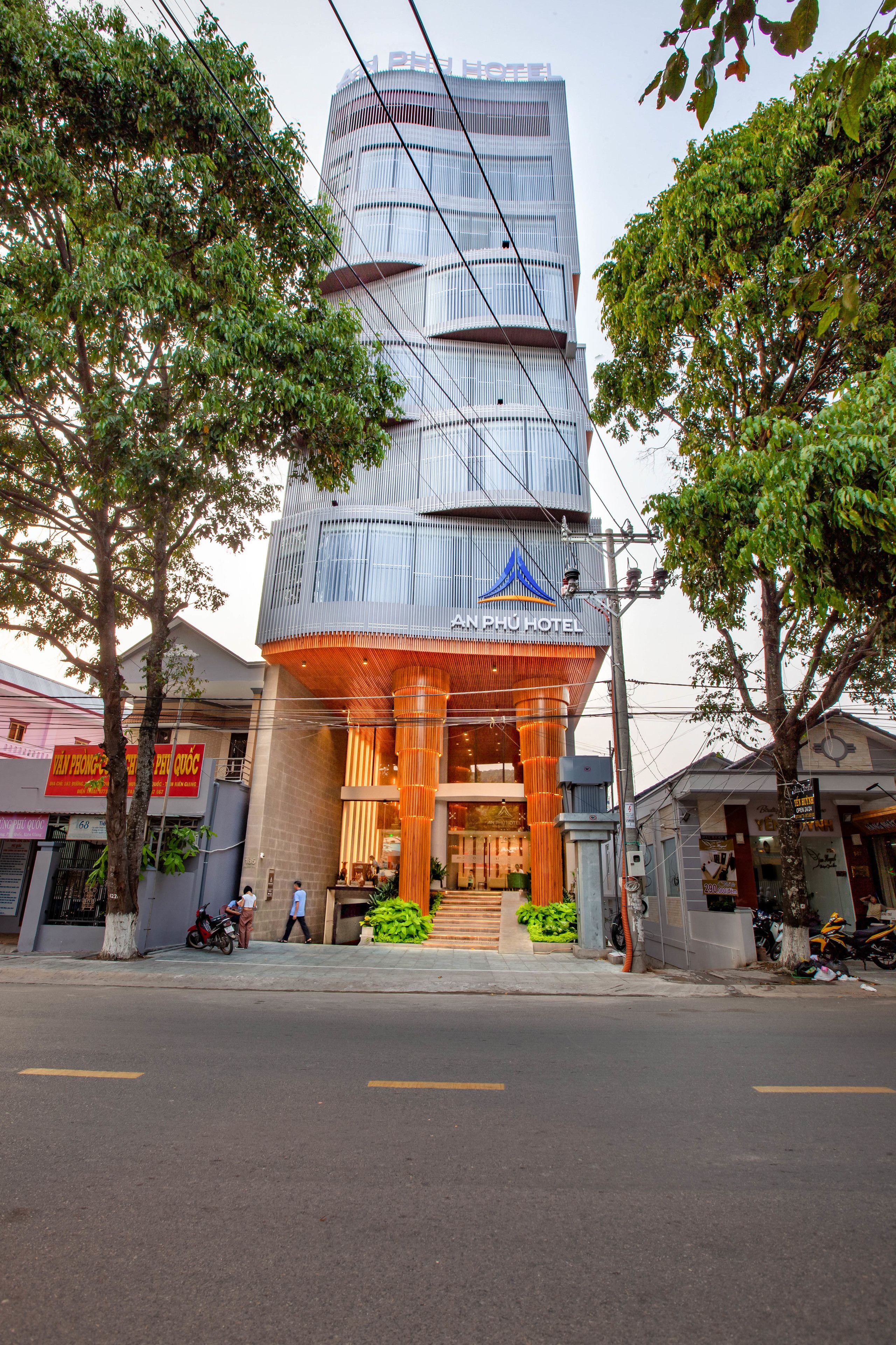 A modern hotel with a prominent entrance, a vertical design, and a sign indicating it is the An Phu Hotel.