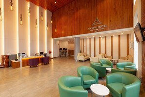 Eine moderne Hotelhalle mit Empfangstresen, Sitzgelegenheiten und Holzvertäfelung.
