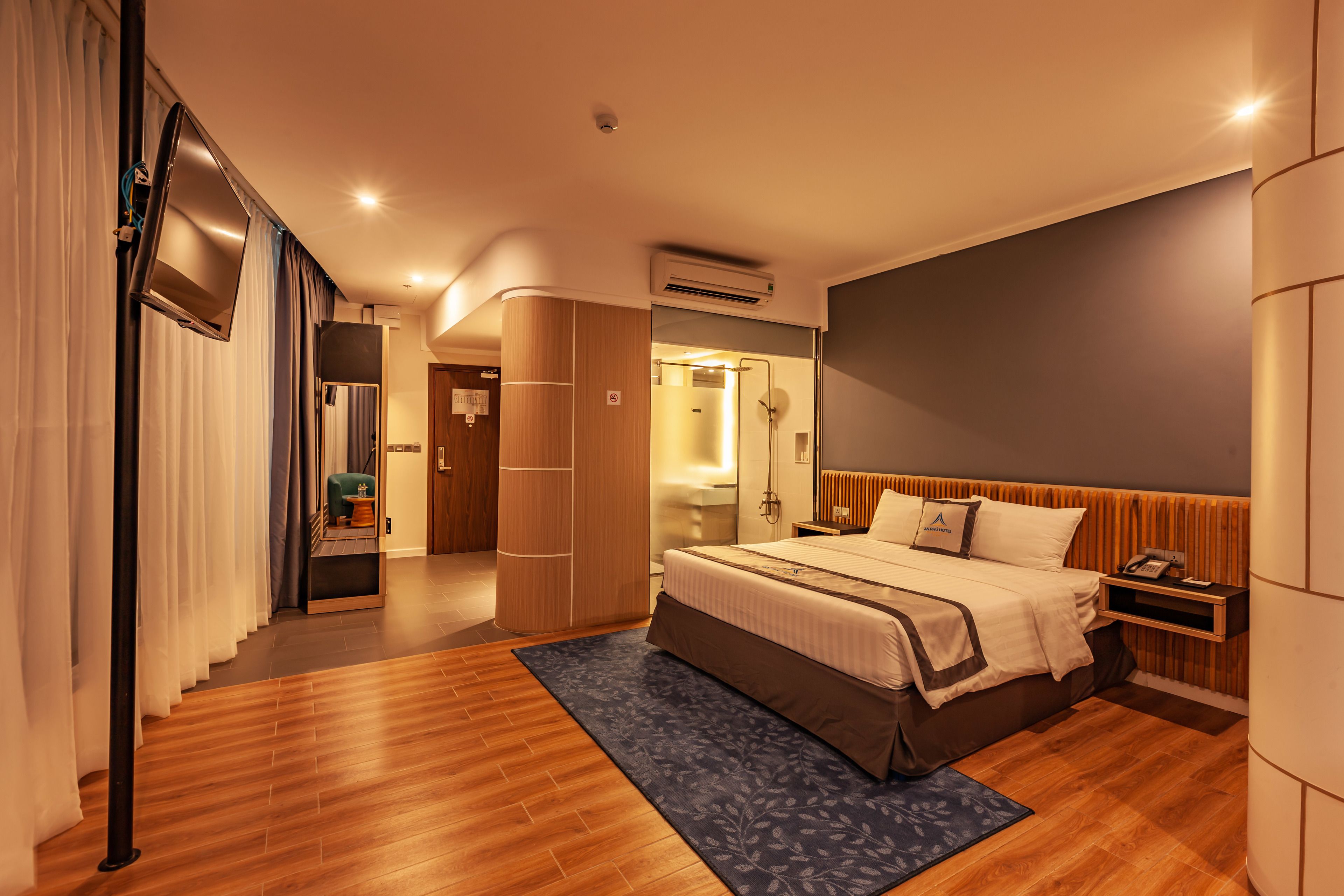 Une chambre d’hôtel moderne dotée d’un grand lit, d’un téléviseur à écran plat, d’un système de climatisation et d’un plancher en bois.