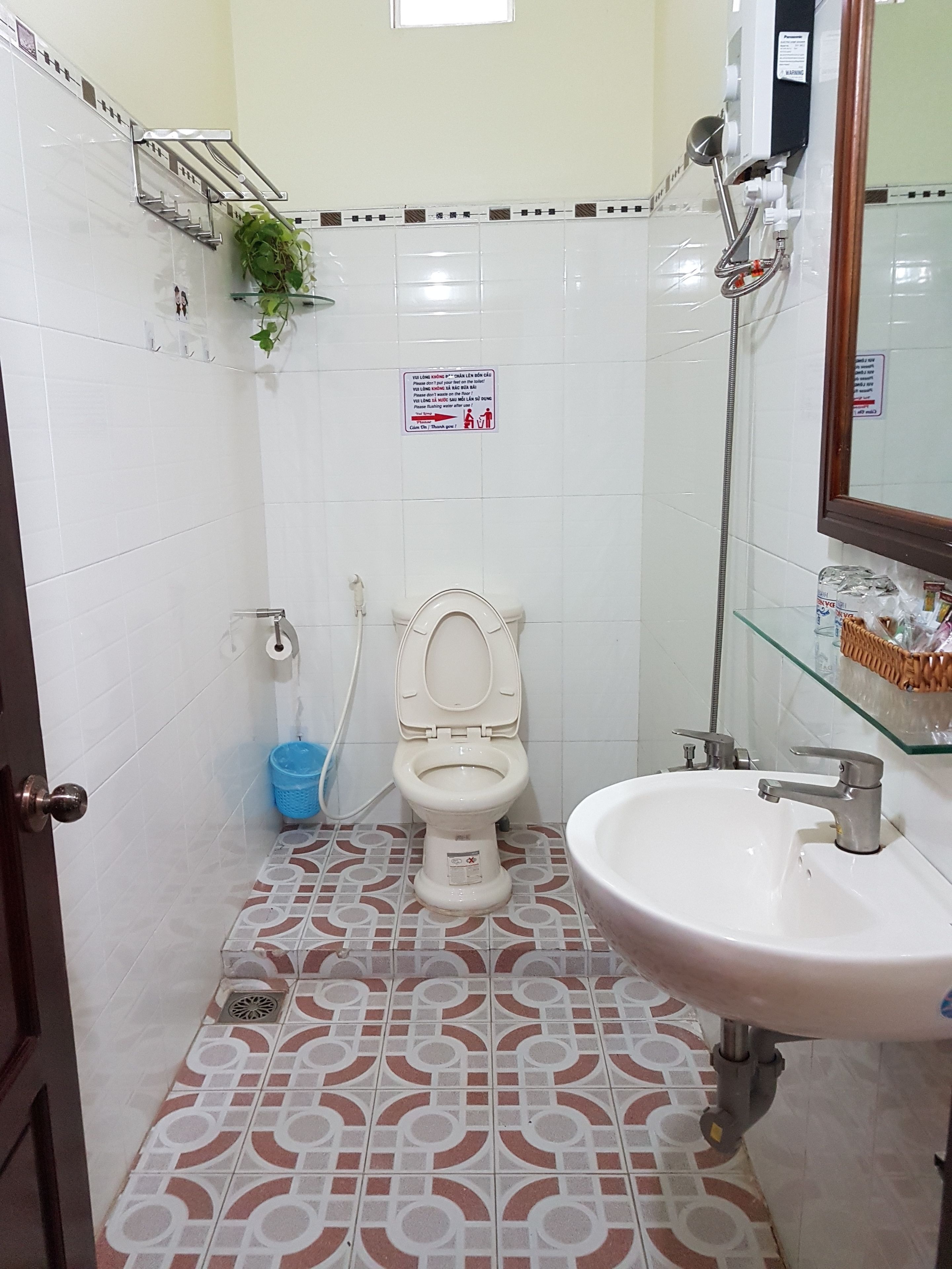 A bathroom with a toilet, sink, shower, and patterned floor tiles.