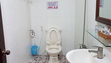 A bathroom with a toilet, sink, shower, and patterned floor tiles.