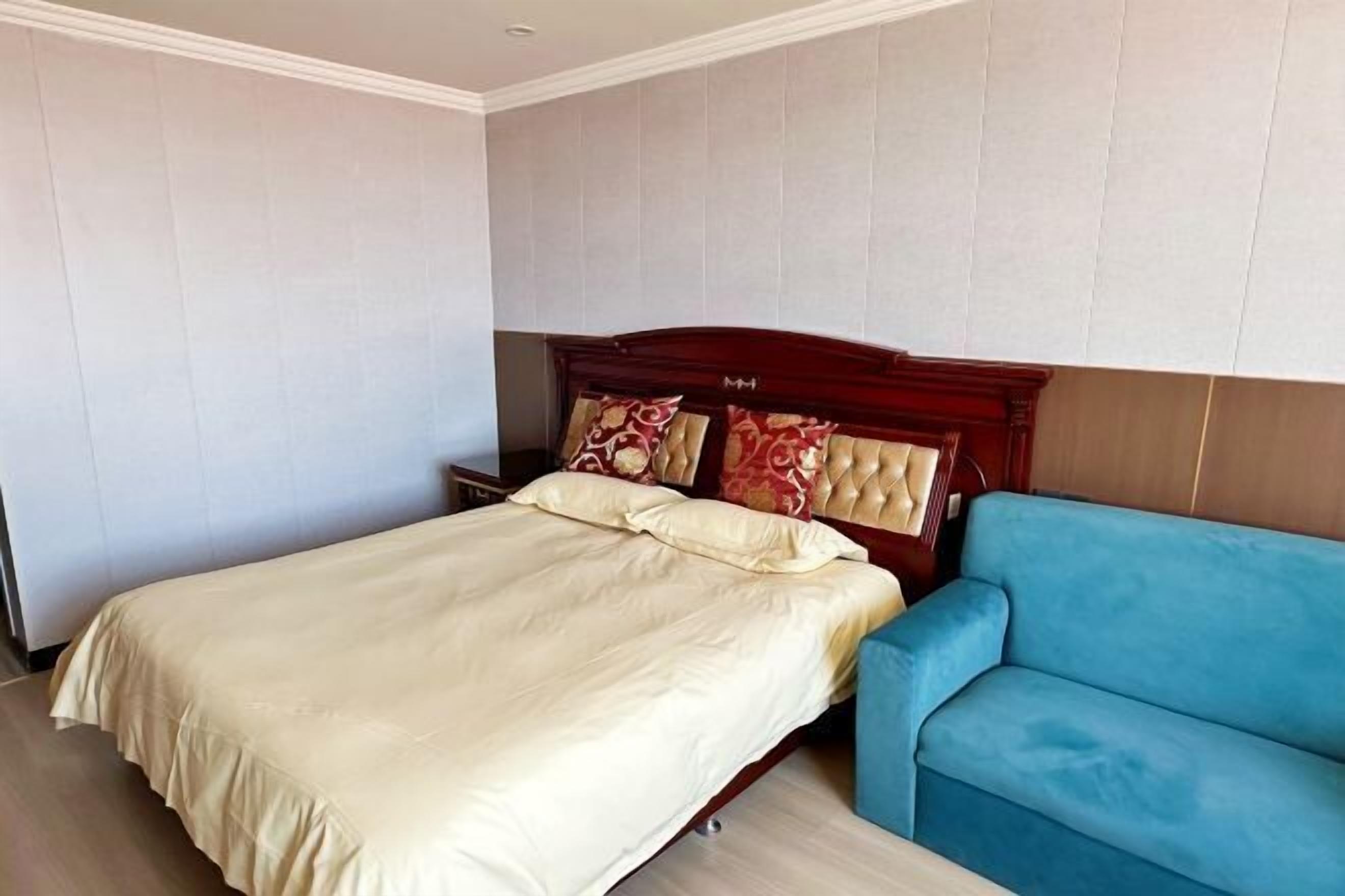 Une chambre à coucher avec un lit, un canapé bleu et une tête de lit en bois.