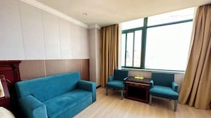 A room with a blue sofa, two matching armchairs, a small wooden table, and a window with curtains. - Zhuoting Hotel (Pinghu)