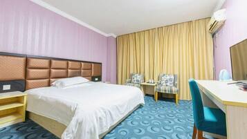 Une chambre d’hôtel équipée d’un lit, d’un bureau, de deux chaises et d’un appareil de climatisation.