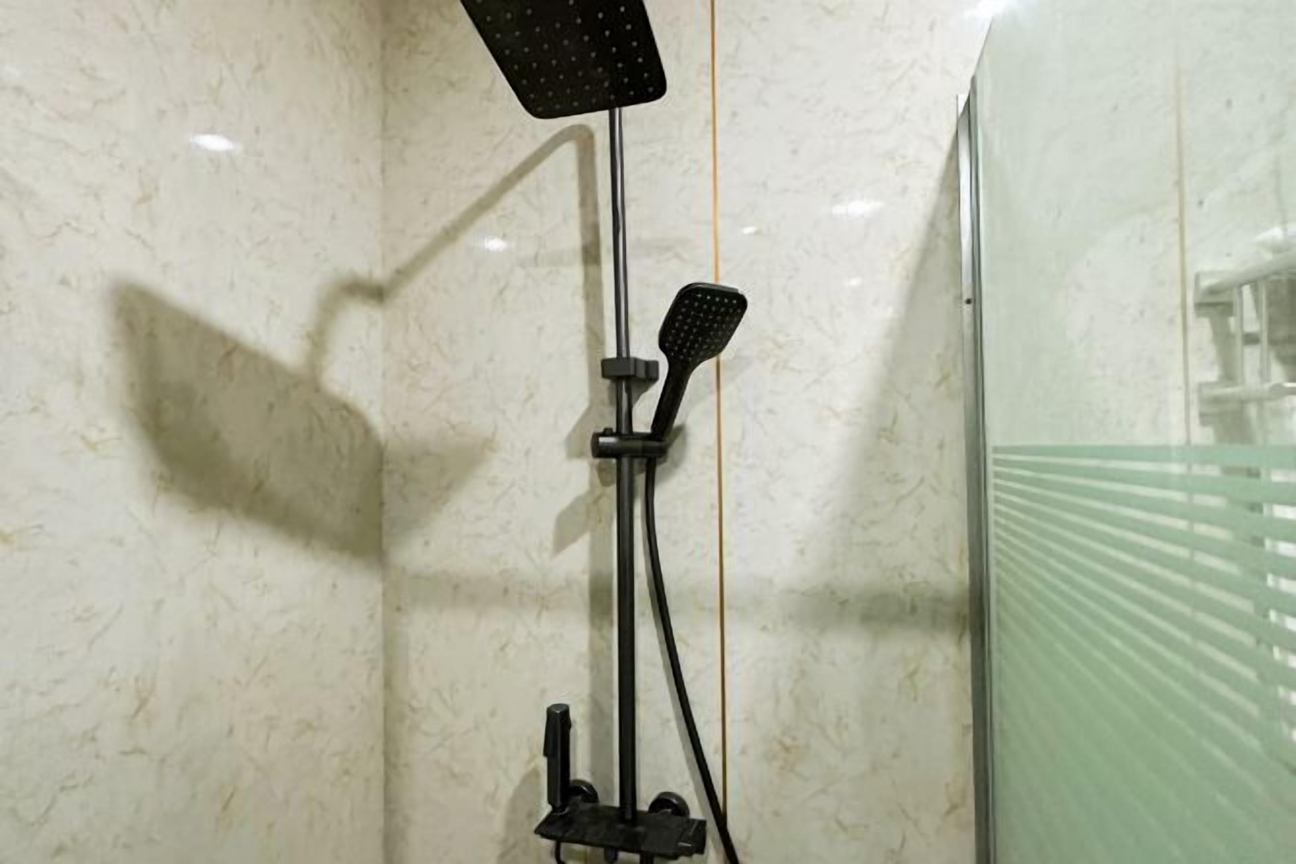 Ducha con cabezal de ducha de mano y un cepillo para el cuerpo, ambos montados en una pared.