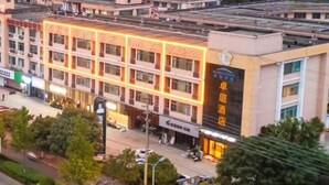 A multi-story hotel with a prominent sign and illuminated windows. - Zhuoting Hotel (Pinghu)