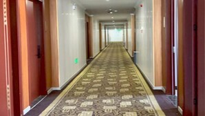 A long, narrow hotel corridor with patterned carpet, wooden doors, and a tiled floor. - Zhuoting Hotel (Pinghu)