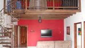 A spacious living room with a red accent wall, a wooden staircase, and a TV mounted on the wall. - Villa Thiago Finca Tradicional (Armenia)