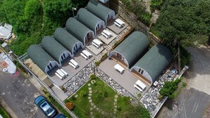 A multi-story building with several cylindrical structures, likely guest rooms, with a central courtyard and surrounding greenery. - HB Bungalow (Xuan Huong - Da Lat)