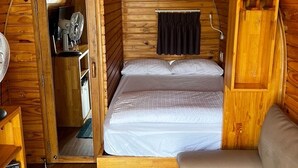 A cozy, wooden interior with a bed, a small seating area, and a door leading to a bathroom. - HB Bungalow (Xuan Huong - Da Lat)