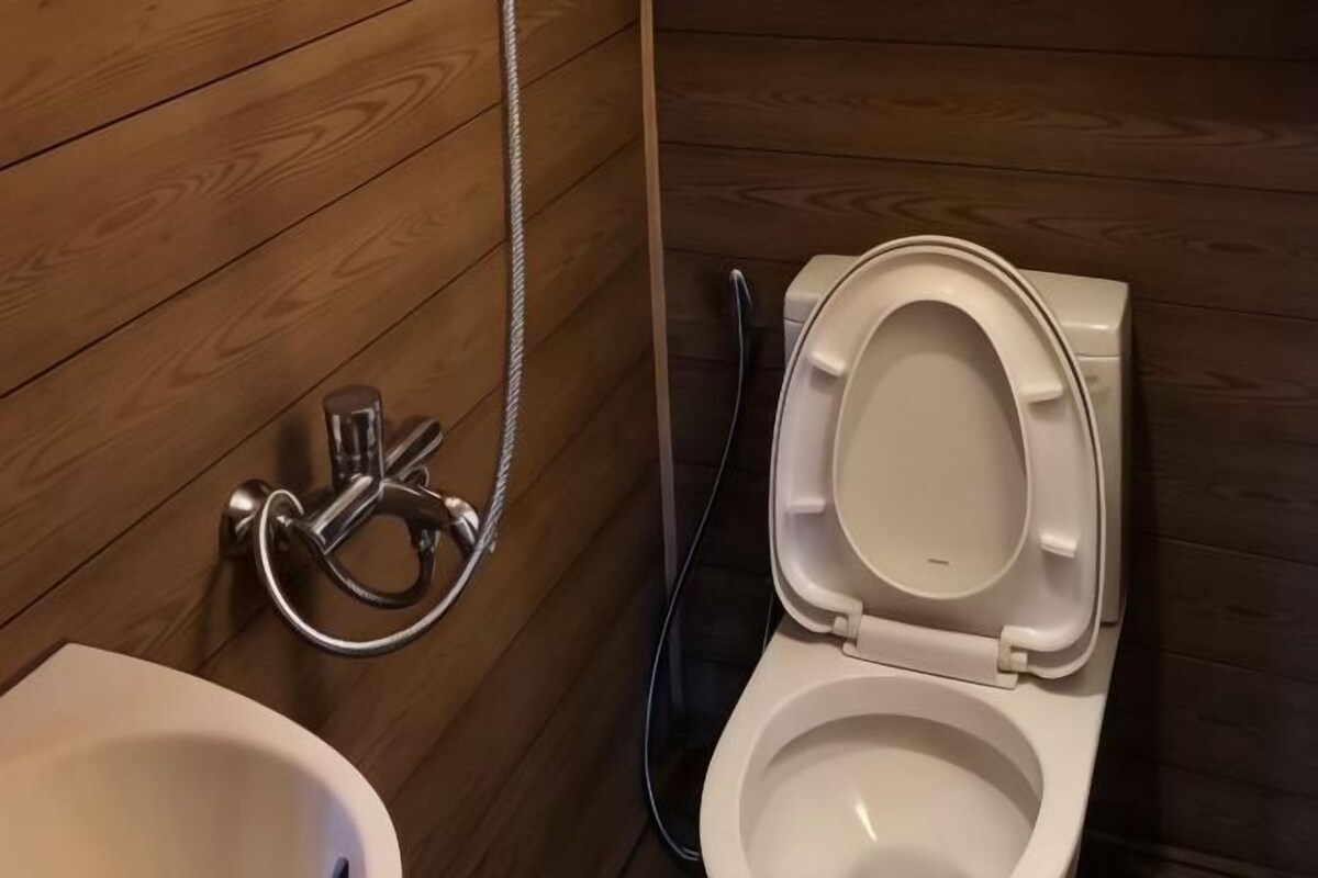 A wooden-paneled bathroom with a toilet and bidet.