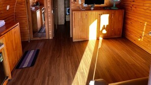 A cozy, wooden interior with a curved ceiling, a television, a fan, and a small kitchenette area. - HB Bungalow (Xuan Huong - Da Lat)