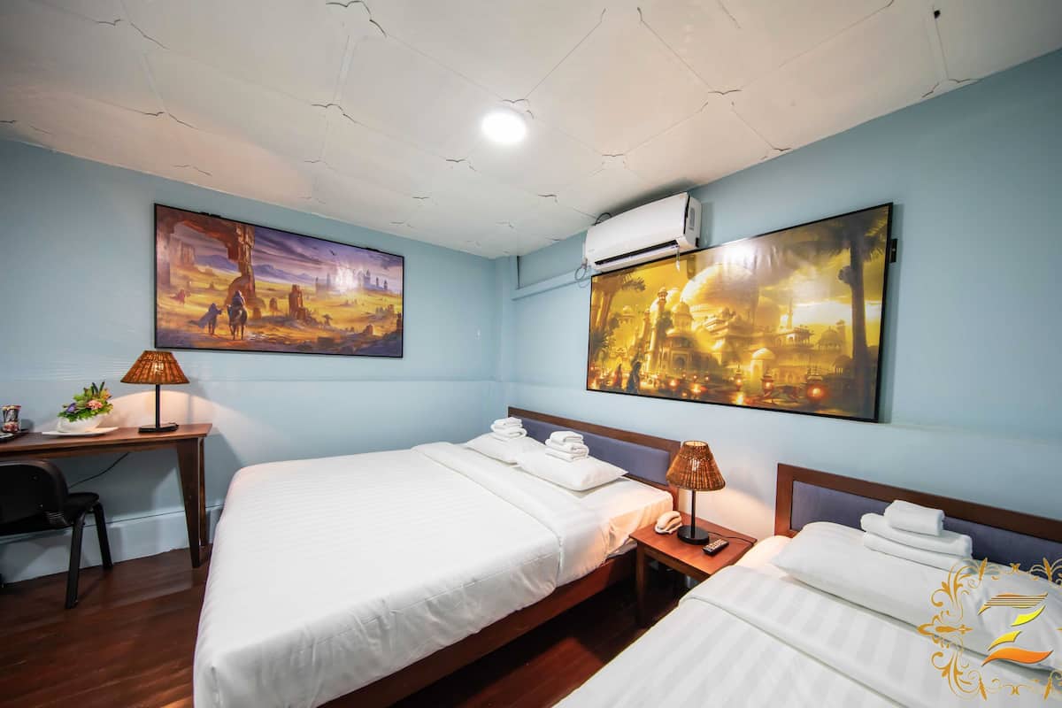 Una camera d'albergo con due letti, una scrivania, una sedia, una lampada e due quadri appesi alle pareti.
