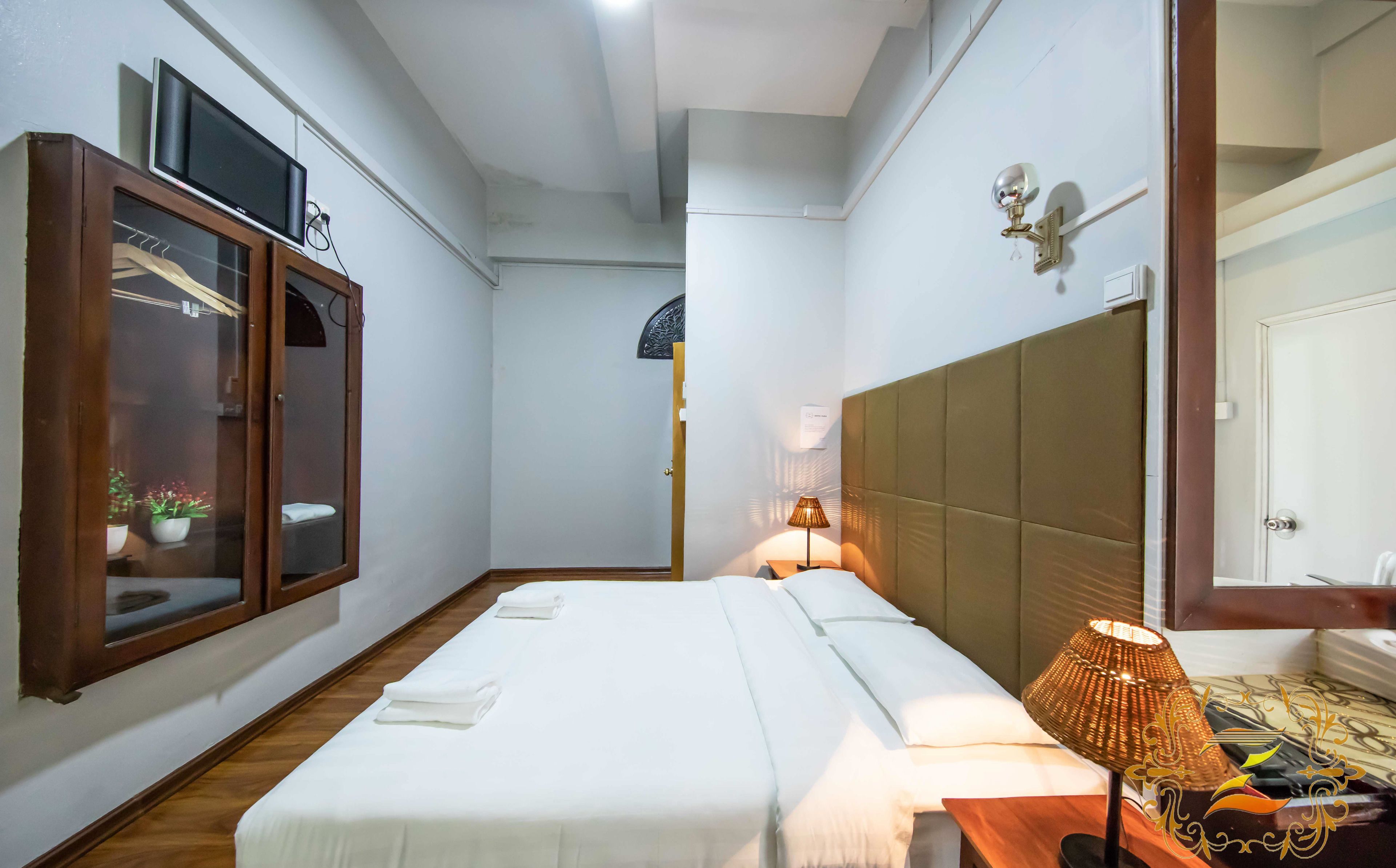 A hotel room with a bed, a nightstand, a lamp, a wardrobe, and a television.
