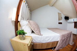 A small, cozy bedroom with a single bed, a wooden nightstand, a potted plant, and a mirror on the wall. - Pousada Brisa do Mar (Imbituba)