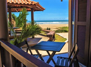 A wooden deck with a table and chairs overlooking a beach. - Pousada Brisa do Mar (Imbituba)