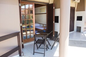 A room with a bed, a table, and chairs. There is a sliding door leading to an outdoor area. - Pousada Brisa do Mar (Imbituba)