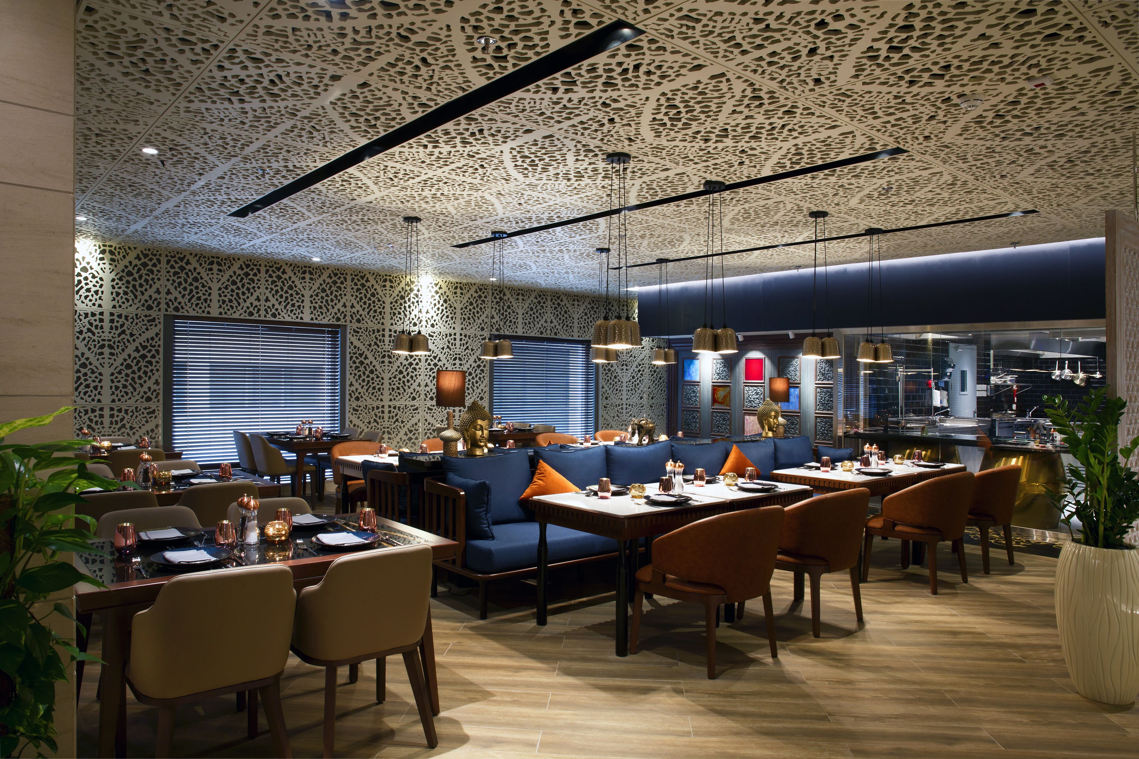 Ein Restaurant mit einem gemusterten Decken, blauen Sitzgelegenheiten und Holztischen.