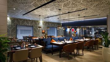 Ein Restaurant mit einem gemusterten Decken, blauen Sitzgelegenheiten und Holztischen.