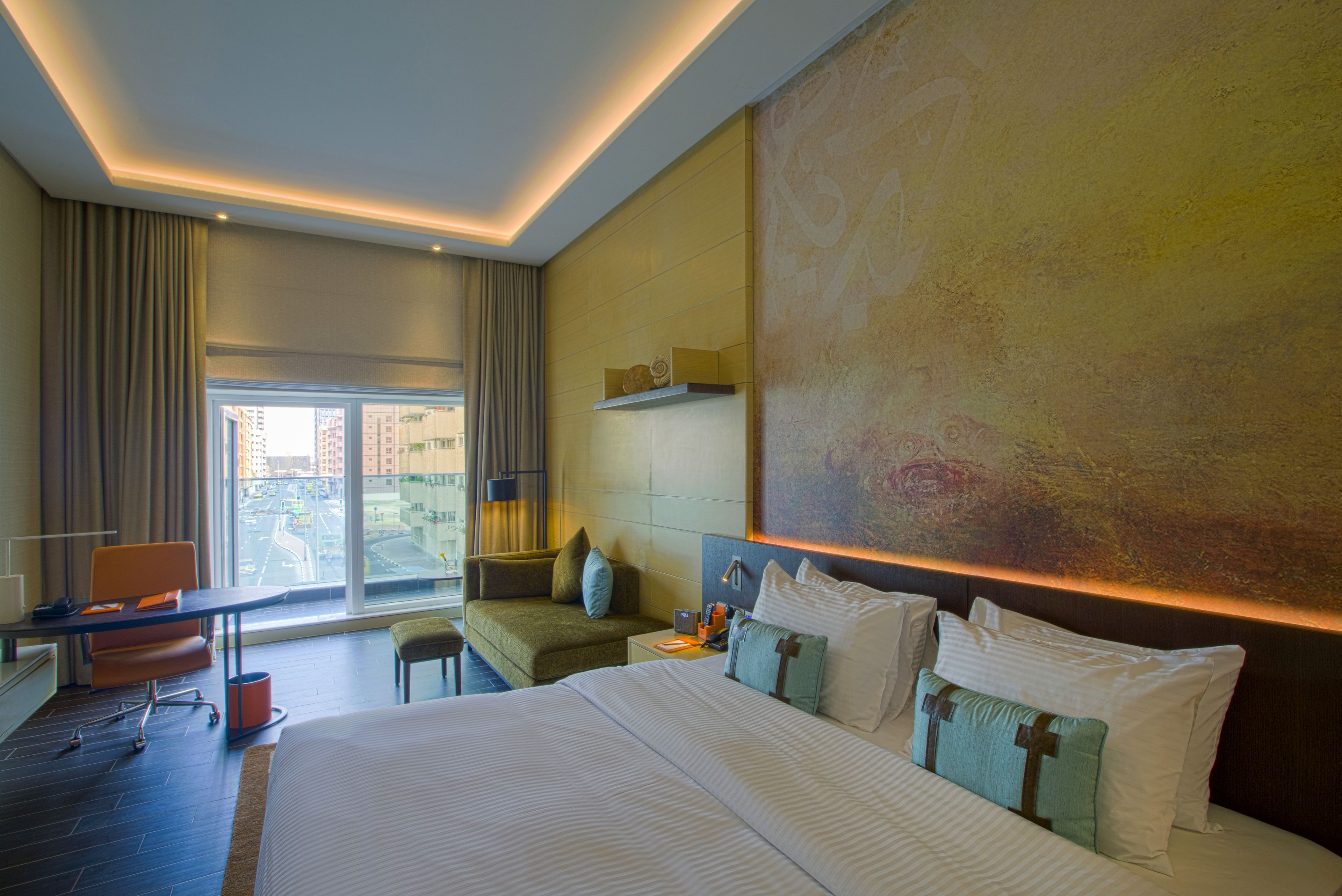 Une chambre d’hôtel moderne, dotée d’un grand lit, d’un bureau et offrant une vue sur la ville par la fenêtre.