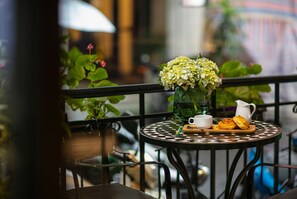 A round table with a white cup, a pitcher, and pastries on a tray. - San Boutique Hotel (Hanoi)