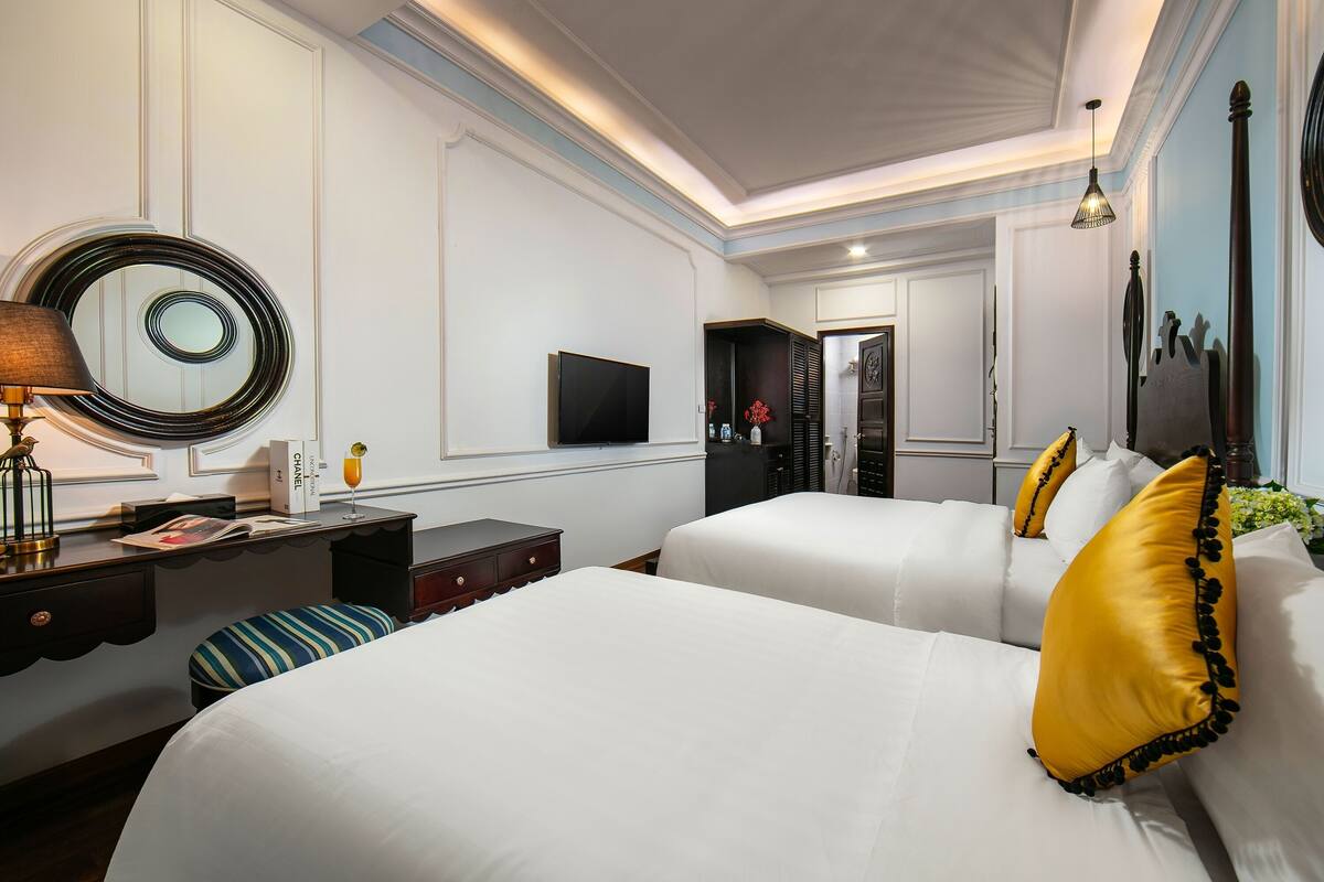 Une chambre d’hôtel avec deux lits, un bureau, une télévision et un miroir.