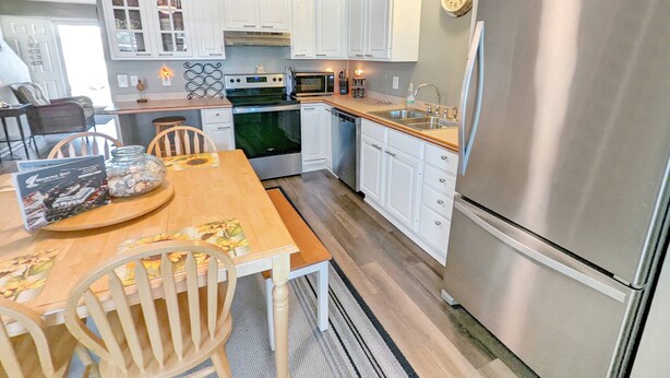 Une cuisine moderne avec des meubles blancs, des appareils en acier inoxydable et une table à manger en bois.