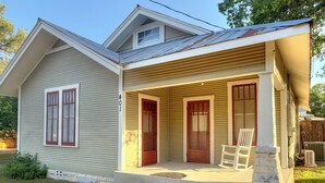 Une maison de plain-pied avec un porche à l’avant, un garage et un petit abri attenant.