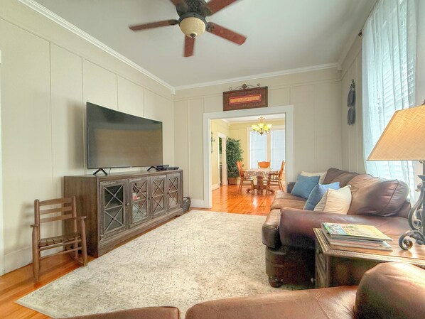 Una sala de estar con televisión, sofá, mesa de centro y ventilador de techo.