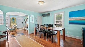 Un vaste espace dédié à la salle à manger, avec une table et des chaises en bois, un grand tableau accroché au mur et une vue par la fenêtre.