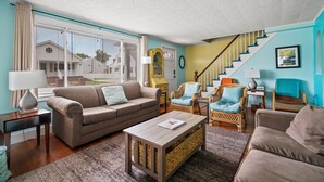 Un salon avec un canapé, des fauteuils, une table basse et un escalier.