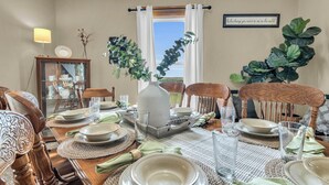 Une salle à manger avec une table dressée pour quatre personnes, agrémentée d’un vase, d’assiettes et de verres.