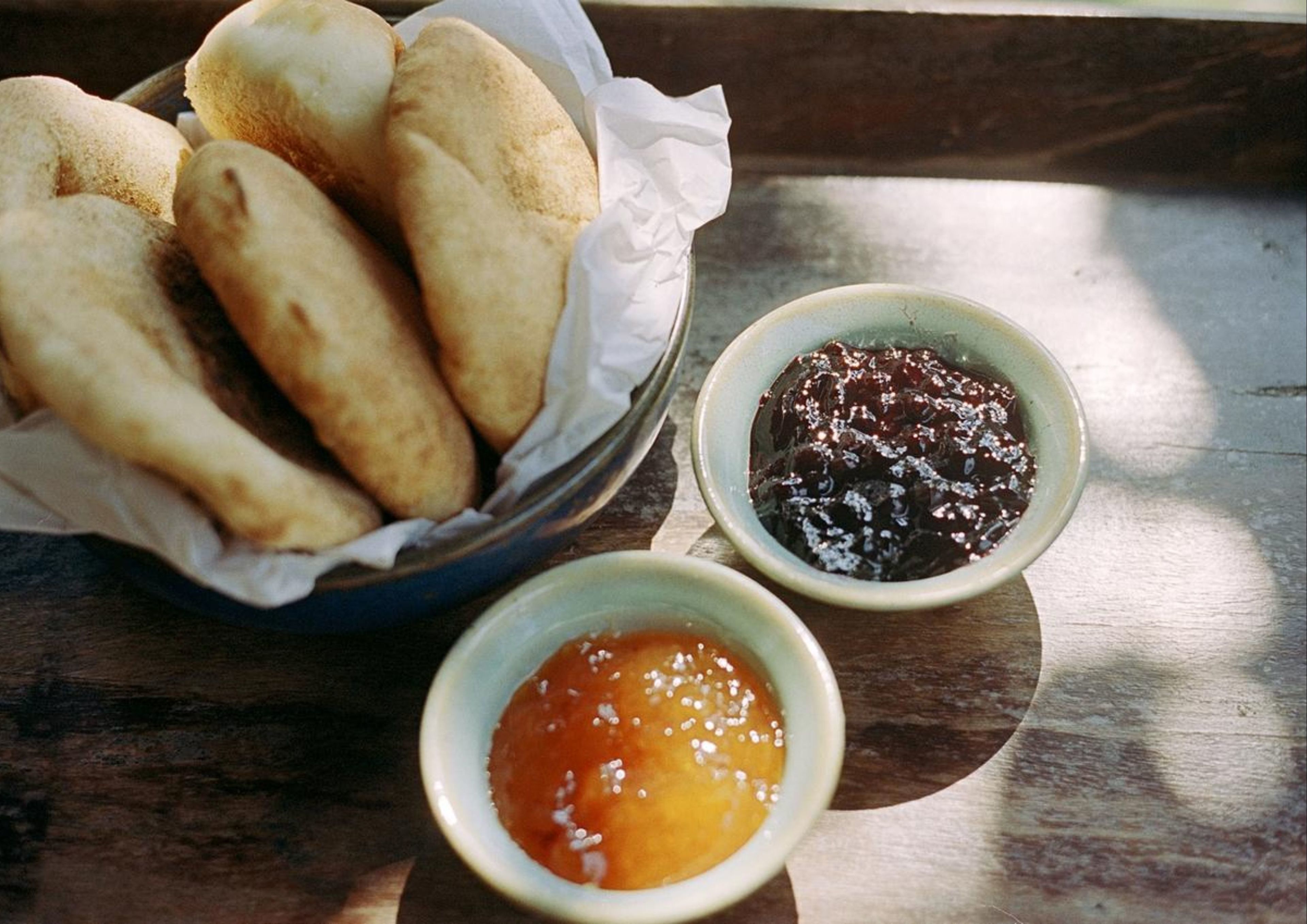 Una bandeja con panecillos y dos recipientes pequeños de mermelada.