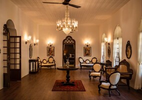 Una habitación amplia con techo alto, candelabros ornamentales y muebles clásicos.