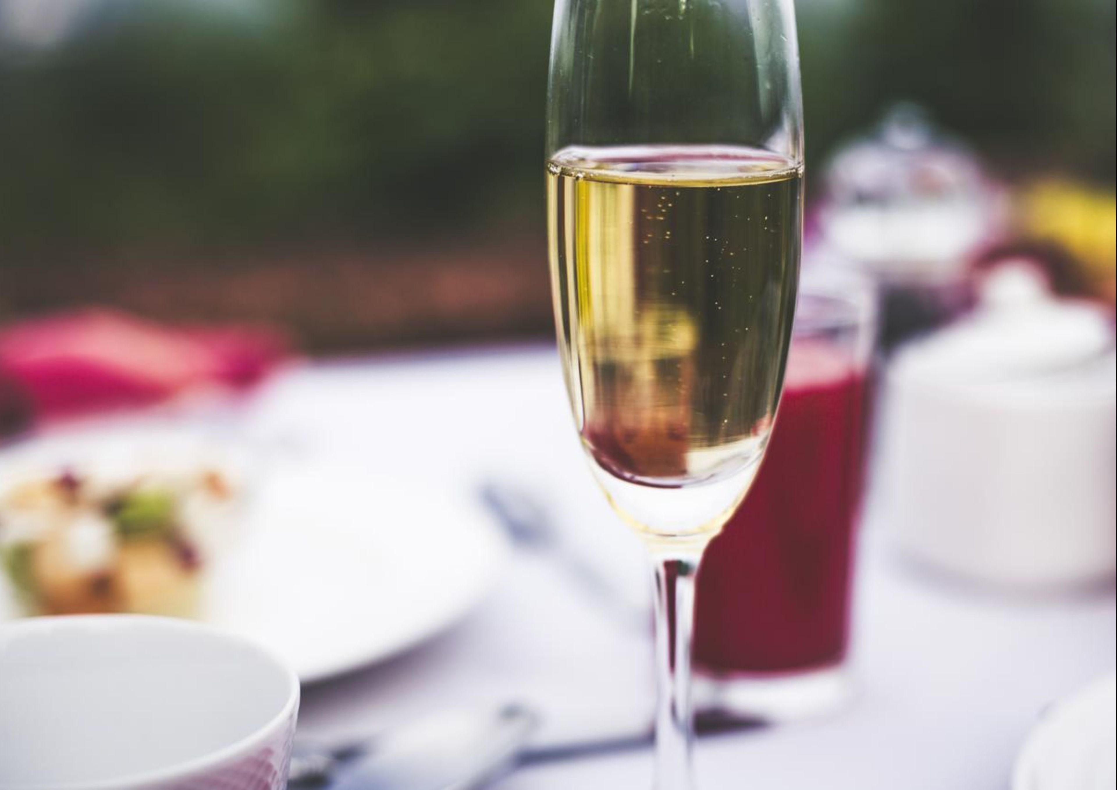 Una copa de vino blanco sobre una mesa con un fondo desenfocado.