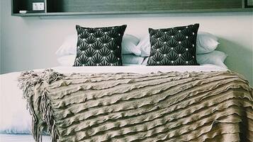 A bed with a textured blanket, two patterned pillows, and a dark headboard.