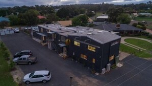 A modern building with a flat roof, a covered parking area, and a small lawn.