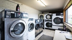 A laundry facility with multiple washing machines, a control panel, and a window providing natural light.