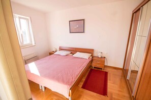 Une chambre à coucher avec un lit, des tables de chevet, une commode, une fenêtre, un tableau au mur et une porte coulissante.