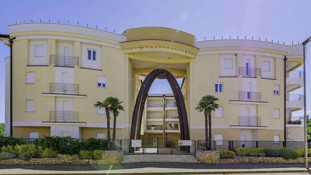 Ein mehrstöckiges Hotel mit einem markanten Bogenportal, Balkonen und einer geschwungenen Fassade.