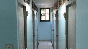 Ein Korridor mit Türen an beiden Seiten, einem gefliesten Boden und einer Decke mit einer Leuchte.