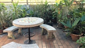 Eine Terrasse mit einem runden Tisch und Bänken, umgeben von Topfpflanzen.