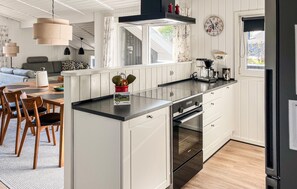 A modern kitchen with white cabinetry, a black countertop, and stainless steel appliances.